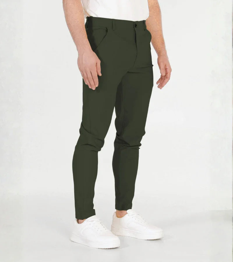 Man wearing slim fit dark green casual pants and white sneakers on white background