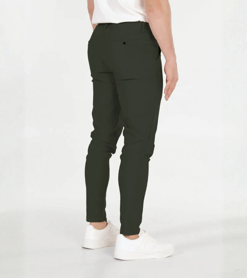 Man wearing black slim-fit pants with a white t-shirt and white sneakers on white background