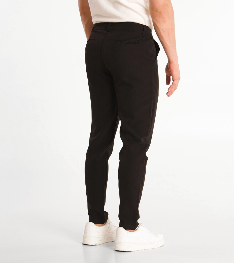 Person wearing black pants and white shoes on a white background