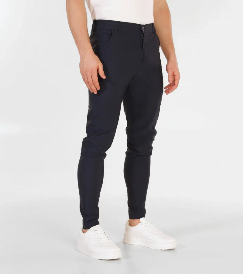 Man wearing slim fit navy blue trousers and white sneakers on white background
