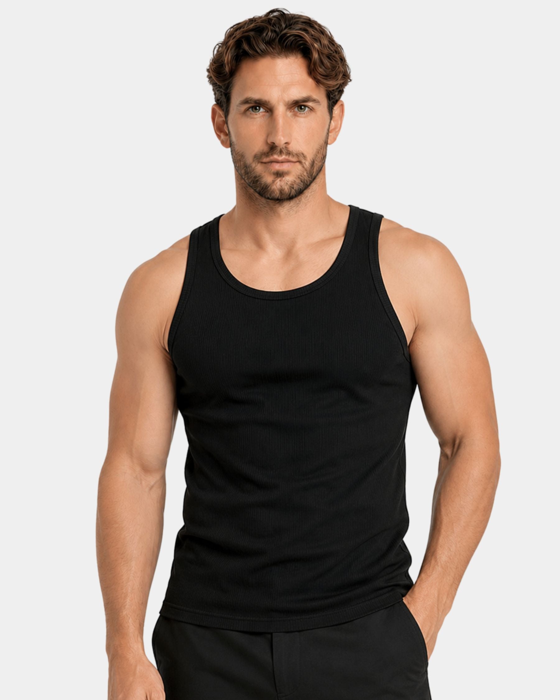 A muscular man wearing a black sleeveless tank top and black pants, standing against a light gray studio background.