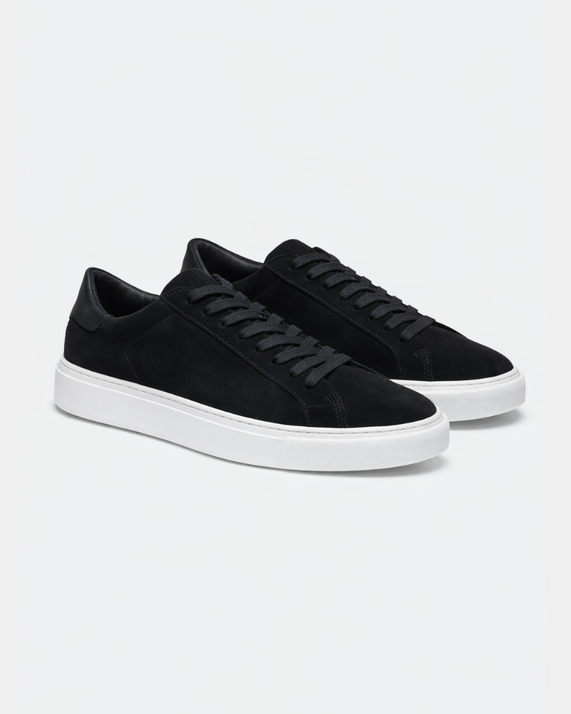 Minimalist luxury black suede trainers featuring tonal laces and premium white soles in a sophisticated angled view.