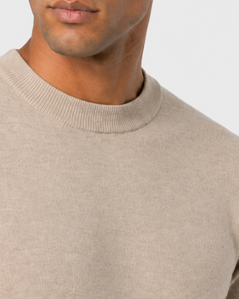 By Alden Oatmeal Crew Neck Knit Sweater worn by a Black male model, close-up front view of neckline and fabric detail, light grey background #Color_Beige