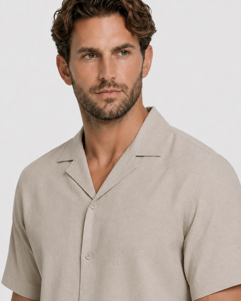 By Alden Stone Linen Camp Collar Shirt worn by a White male model, close-up portrait view of collar and button detail, light grey background #color_stone