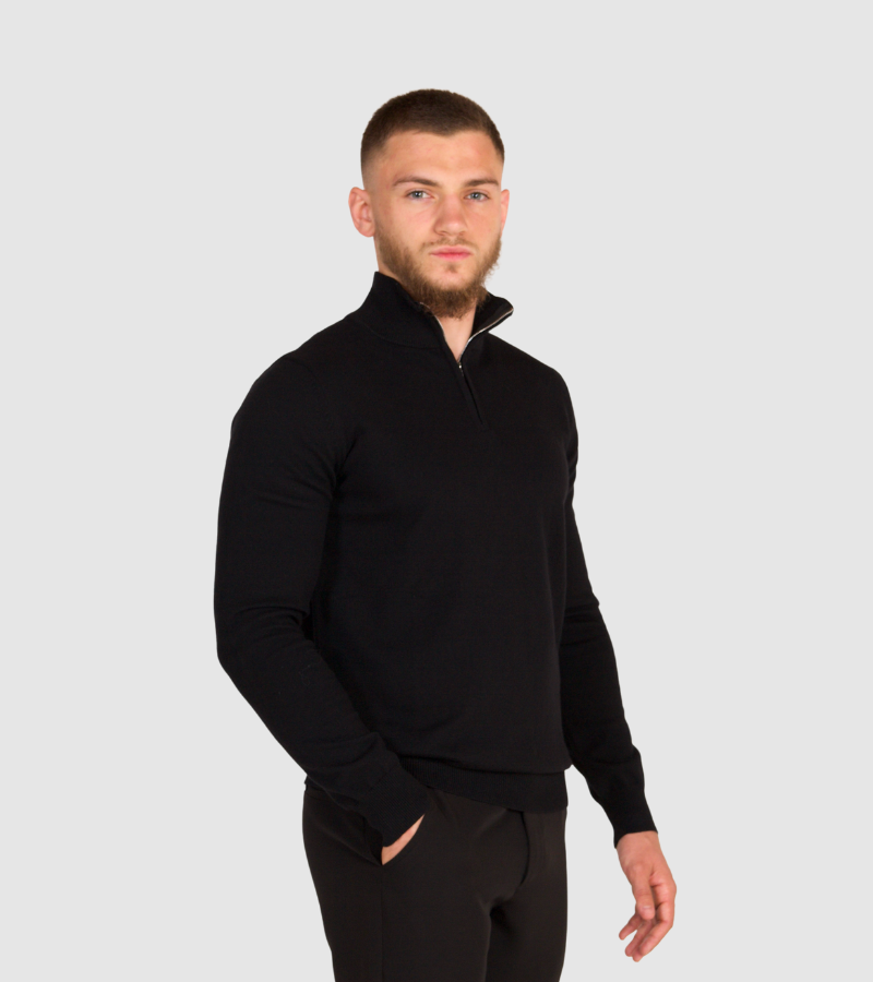 Man wearing a black quarter-zip sweatshirt on a light gray background