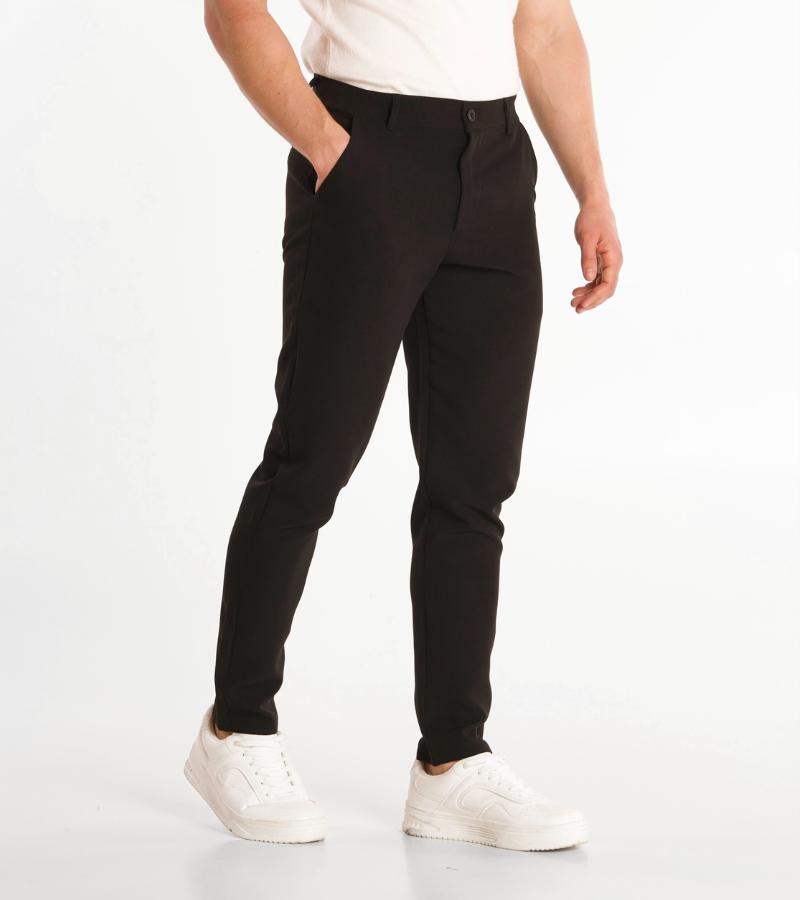 Person wearing black pants and white shoes on a white background