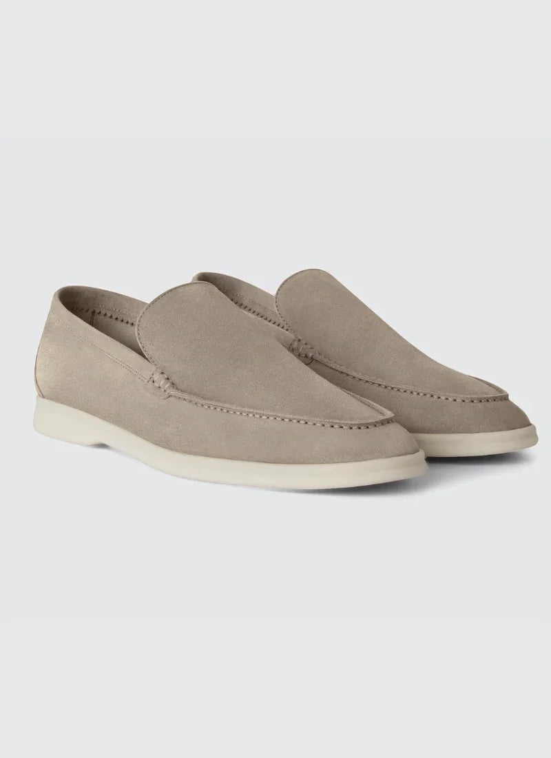 Pair of light gray suede loafers with white rubber soles on a white background