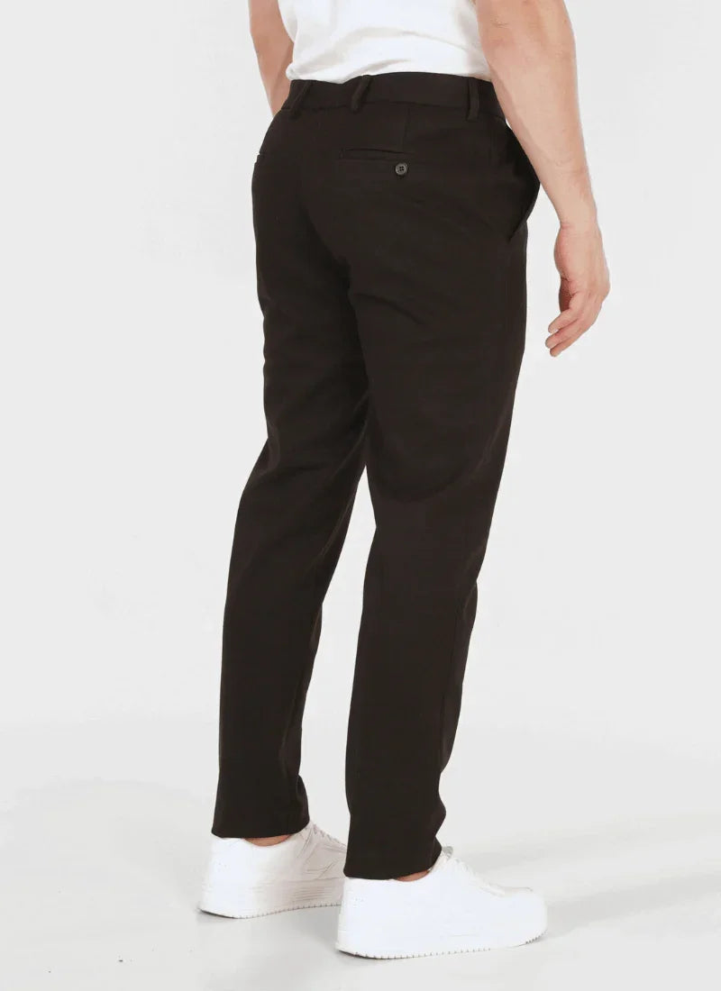Men's black classic wool mix trousers with buttoned back pocket, worn with white sneakers