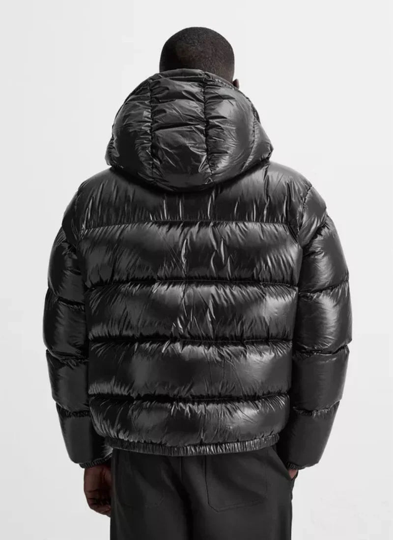 Back view of person wearing shiny black puffer jacket with hood and black pants