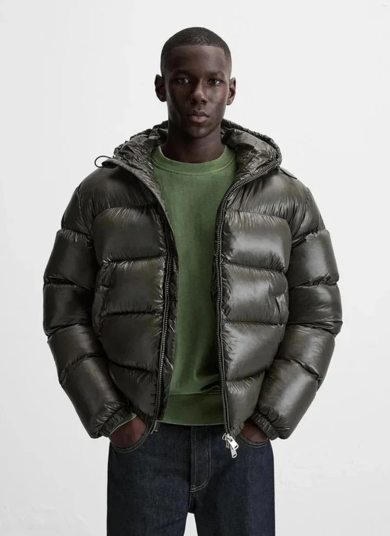 Man wearing Alden Ash black shiny down puffer jacket with hood, green sweatshirt, and dark jeans
