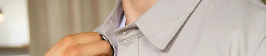 close-up of person adjusting beige casual shirt collar indoors with blurred background