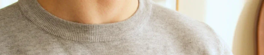 Man wearing cozy gray crewneck sweater in bright indoor setting