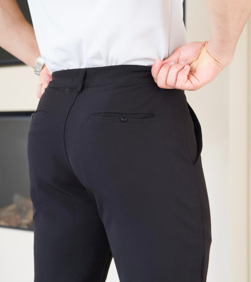 Person wearing black pants with a white shirt, standing indoors.
