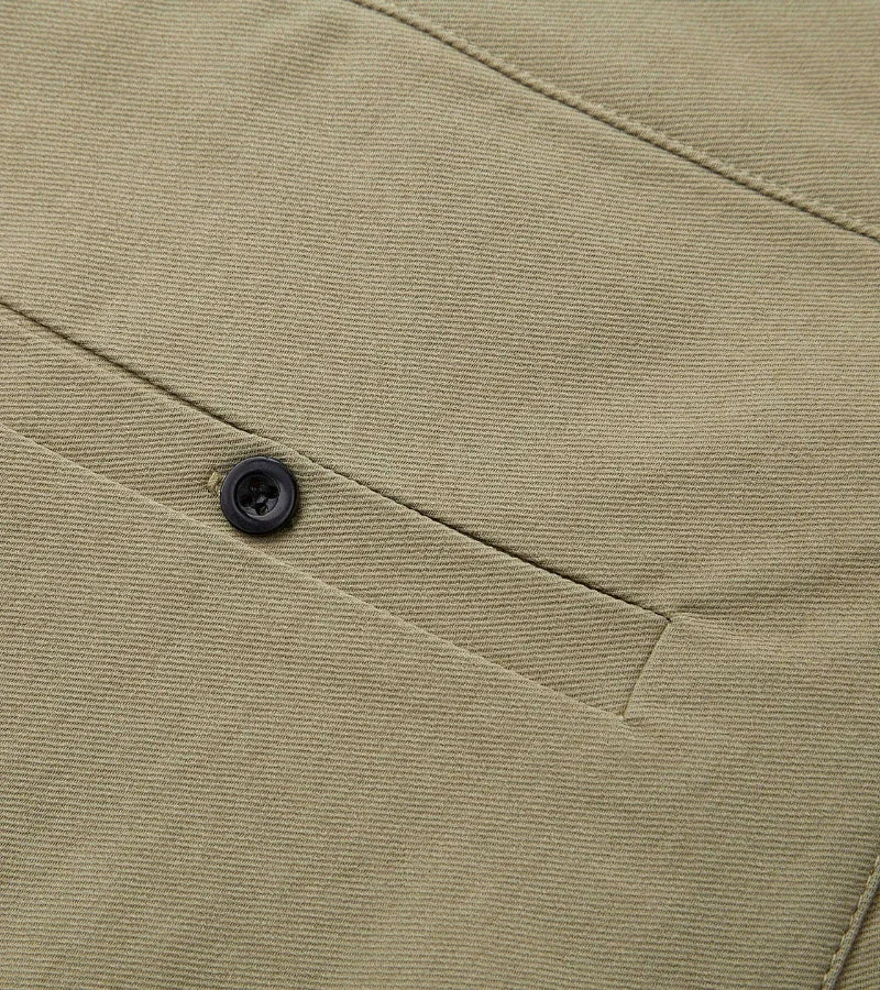 Close-up of beige fabric pocket with black button on casual pants or jacket