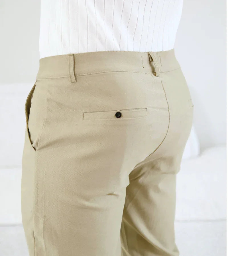 Close-up of beige men's trousers with back button pocket and side pocket worn with white ribbed shirt
