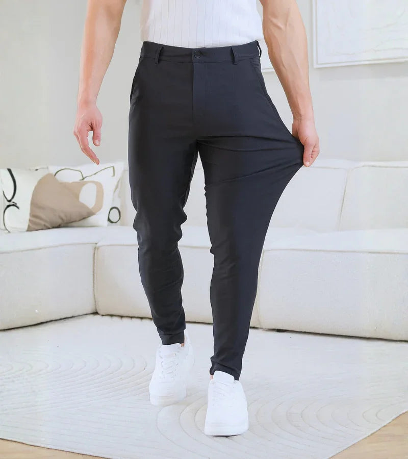 Man wearing black stretch pants and white sneakers standing in modern living room