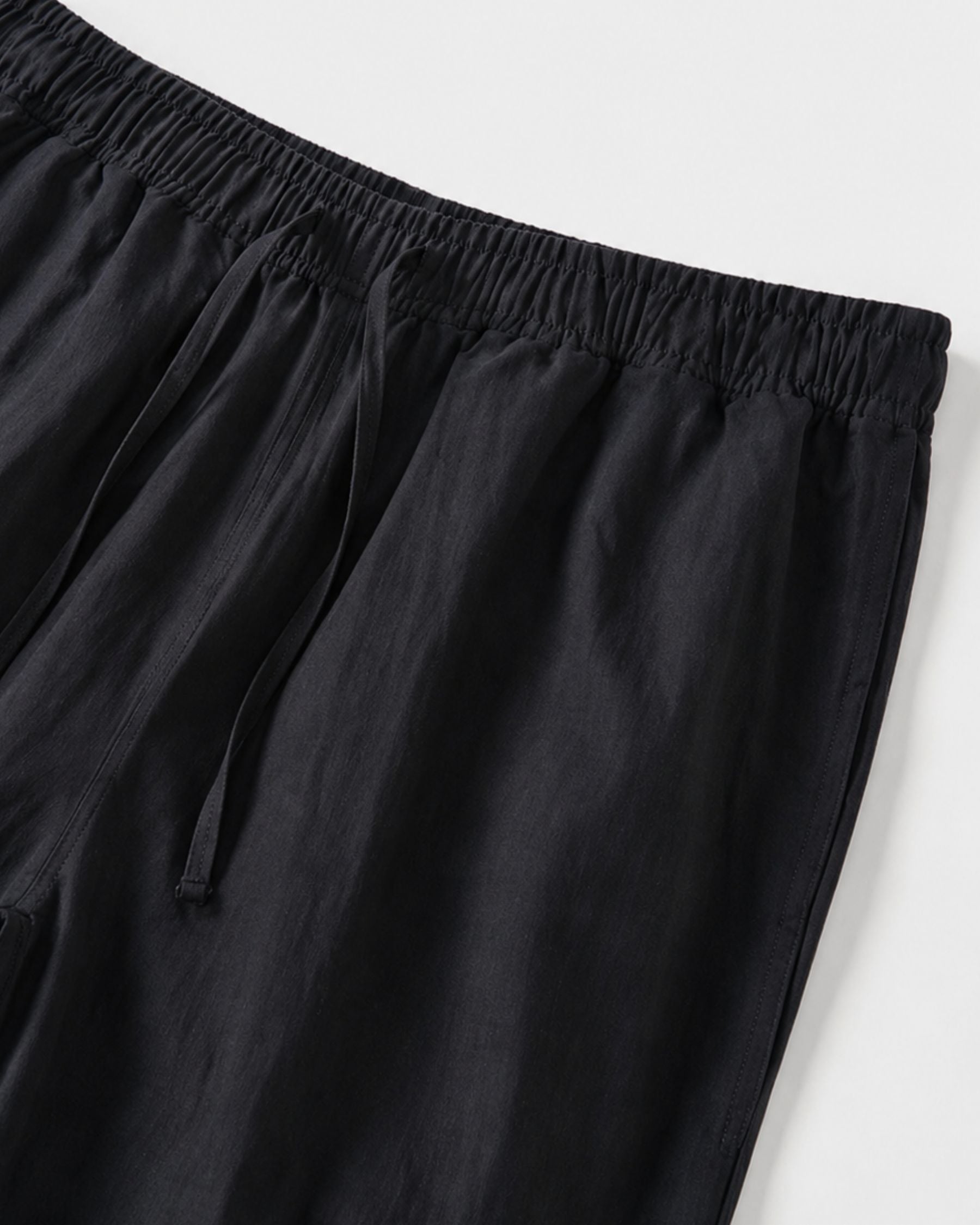 By Alden navy linen drawstring trousers, close-up detail of elastic waistband and drawstring, light gray background #color_navy