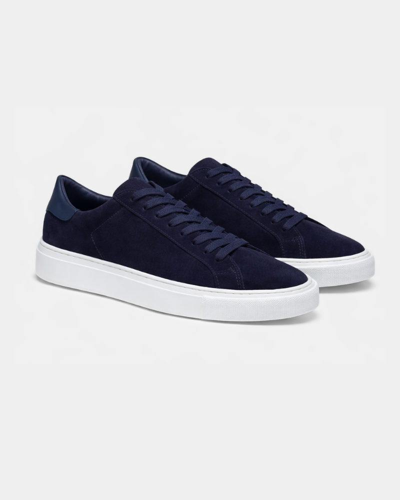 Luxury navy suede trainers with matching flat laces and white midsoles, presented in an elegant angled pair view.