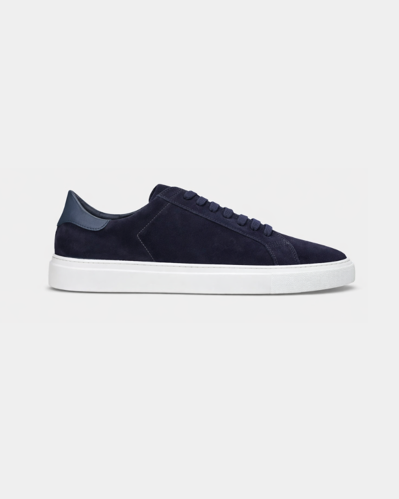 Minimalist luxury navy blue suede trainers featuring a deep blue leather heel tab and a crisp white rubber sole.