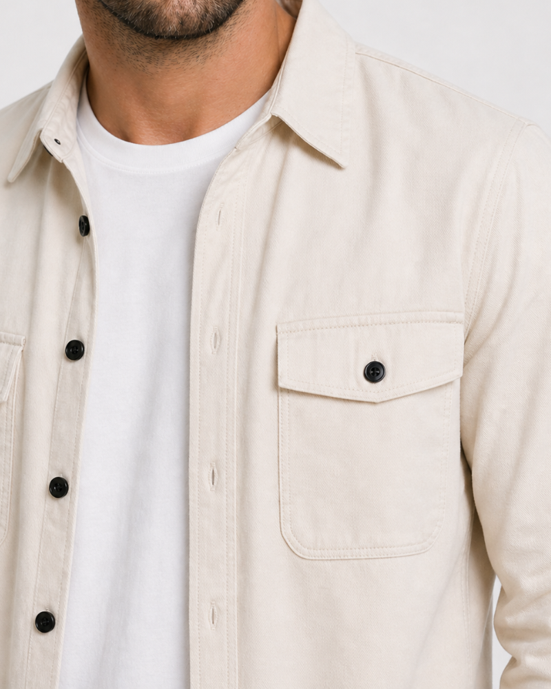 Close-up of a person wearing a By Alden beige button-up shirt over a white t-shirt. #color_deep stone