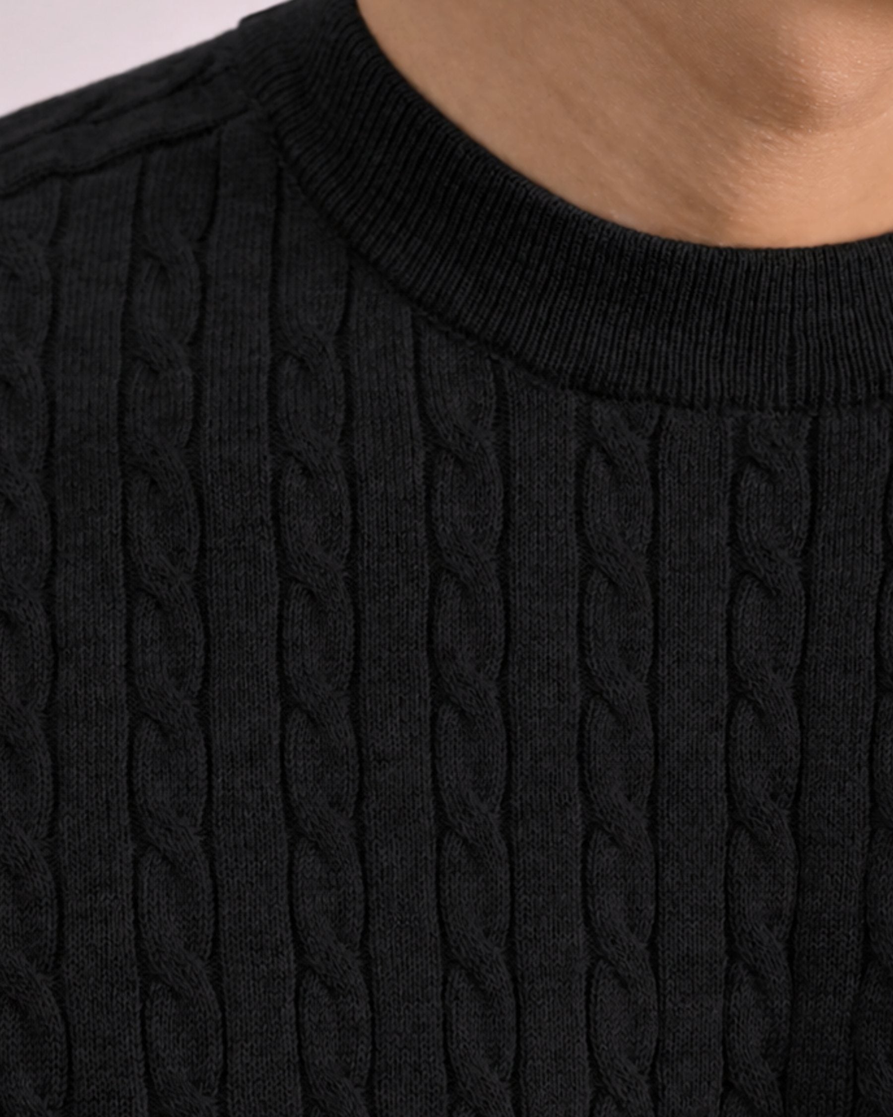 By Alden black cable-knit short-sleeve sweater, close-up detail of crew neck and knit texture, light gray background #color_black
