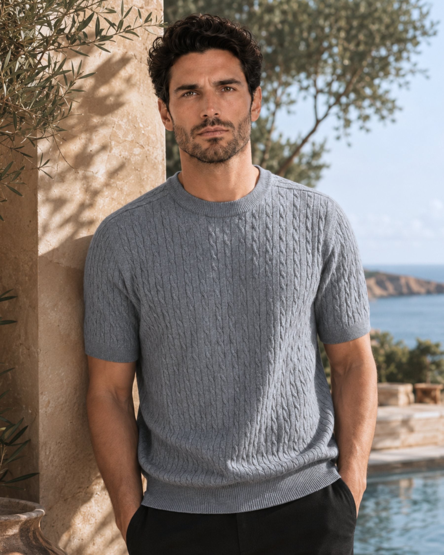 By Alden gray cable-knit short-sleeve sweater on male model, front view upper body, outdoor background #color_gray