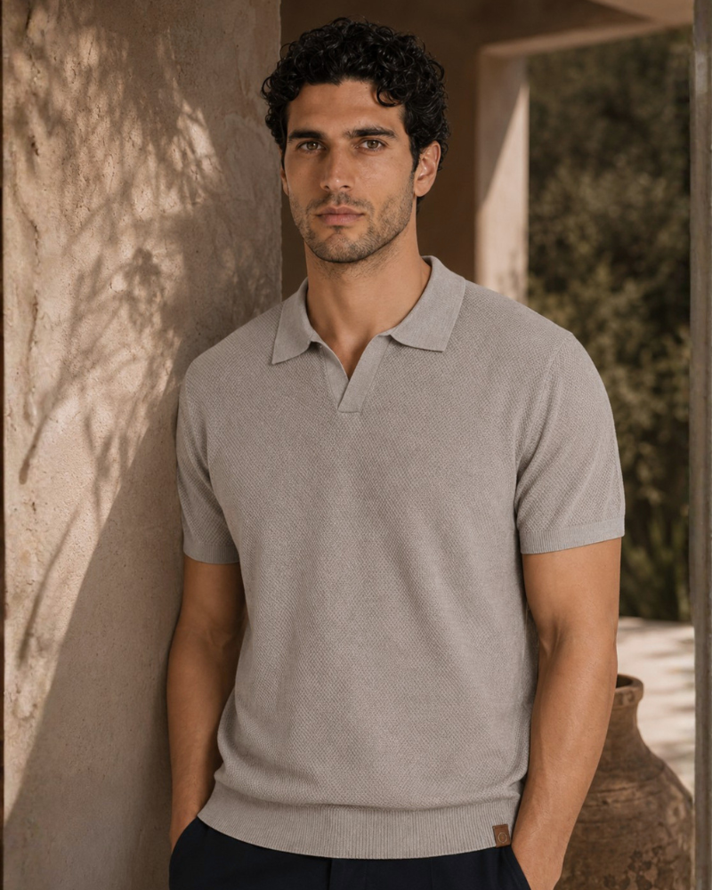 By Alden light gray knit polo shirt on male model, front view, upper body, warm beige wall background. #Color_deep stone