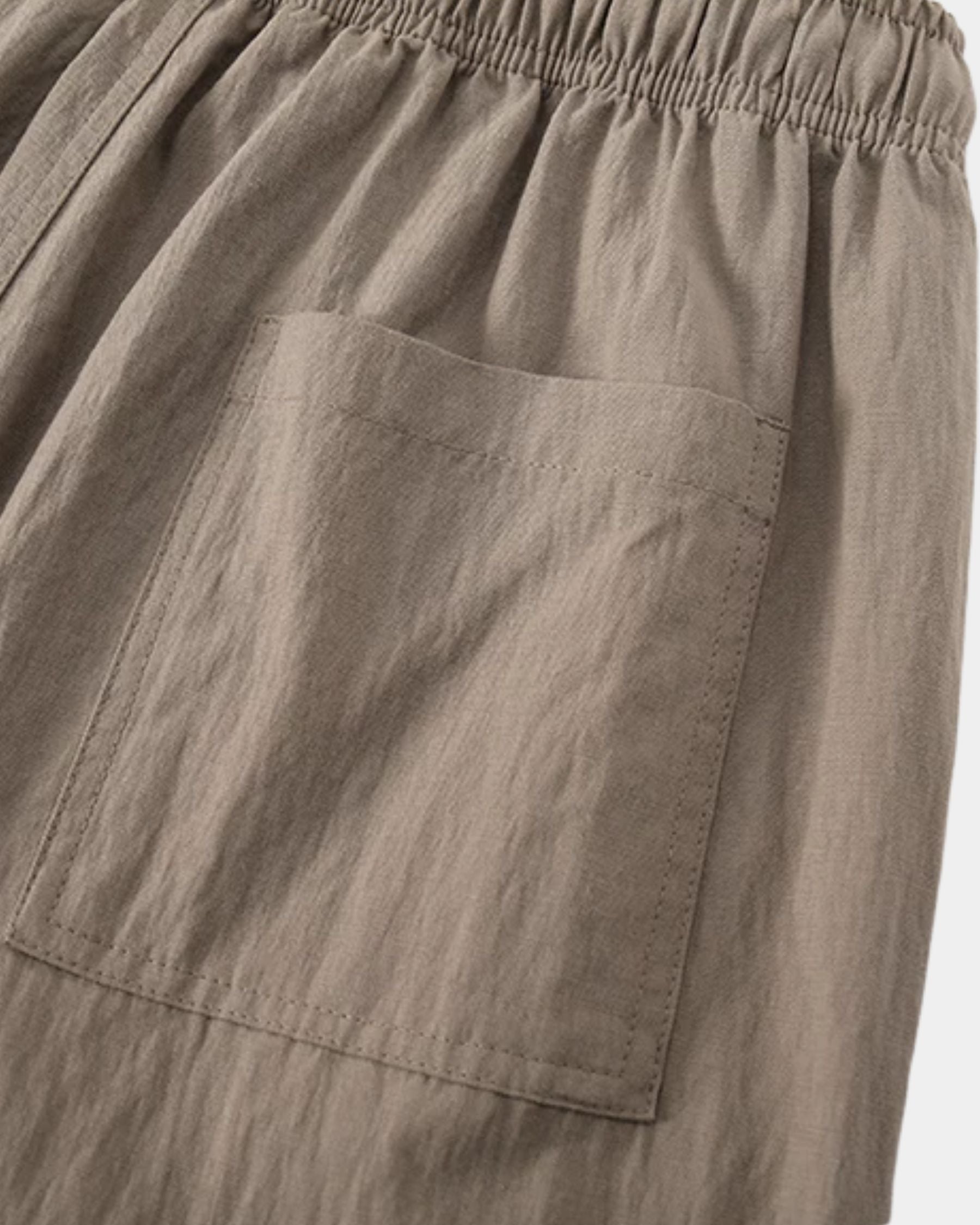 By Alden taupe linen drawstring trousers, close-up detail of back pocket and fabric texture, light gray background #color_taupe