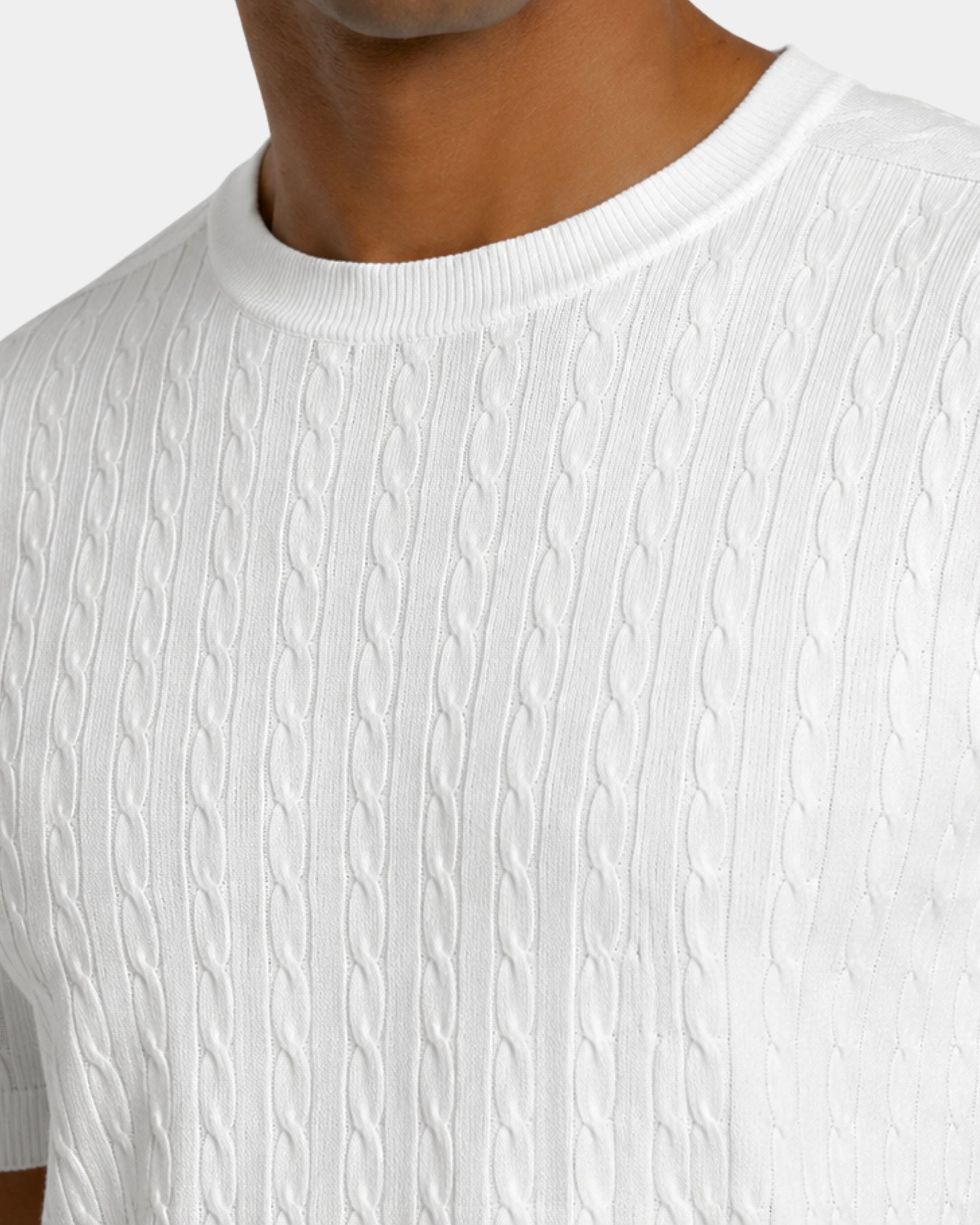 By Alden white cable-knit short-sleeve sweater, close-up detail of crew neck and knit texture, light gray background #color_white