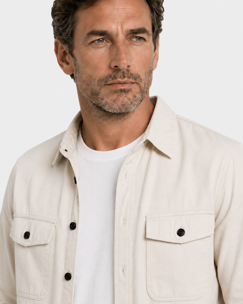 Close-up of a person wearing a By Alden stone button-up shirt over a white t-shirt. #color_stone