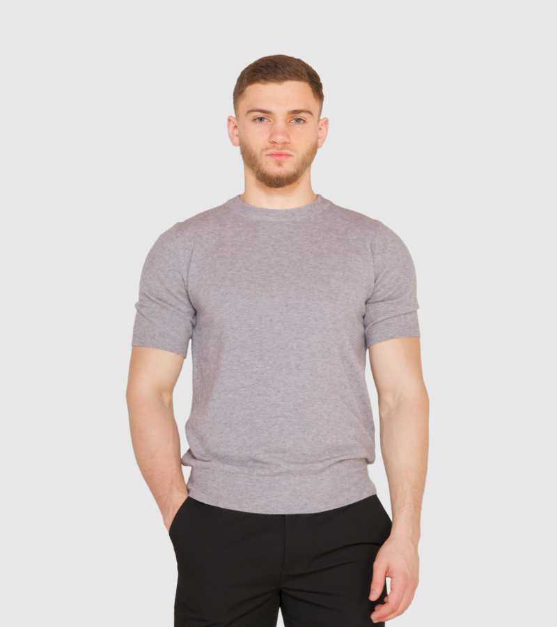 Man wearing a gray sweater and black pants on a white background